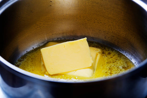 Butter melting in a pan on the stove stock photo