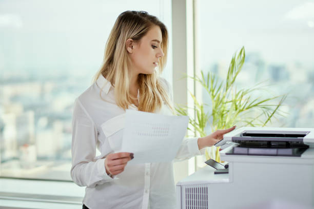 jeune femme d’affaires imprime sur l’imprimante au bureau - fax paper photos et images de collection