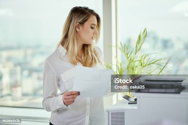 Young Businesswoman Prints On The Printer In The Office Stock Photo - Download Image Now