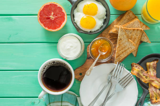 istock Summer breakfast - eggs, bacon, toast, jam, coffee, juice 902855428