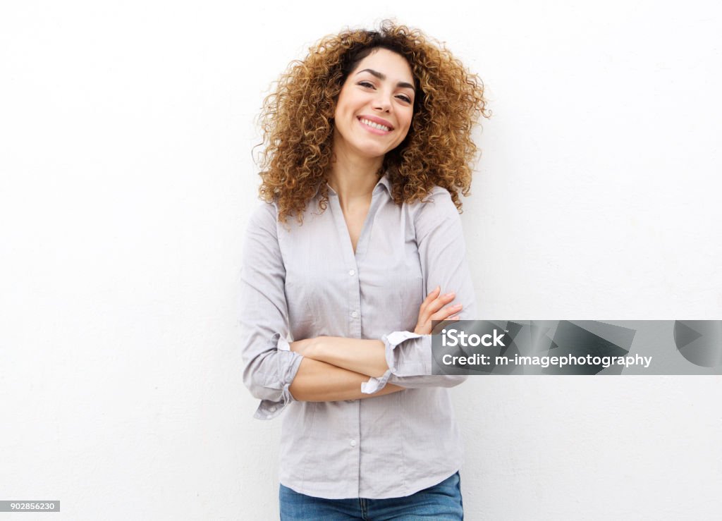 smiling young woman with curly hair against white background Portrait of smiling young woman with curly hair against white background White Background Stock Photo