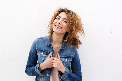 Portrait of young woman smiling with jeans jacket against white background