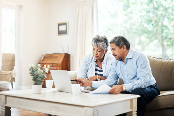 Planning our retirement together Shot of a senior couple using a laptop together at home pension photos stock pictures, royalty-free photos & images