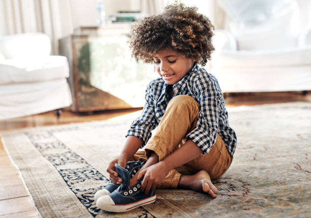 Putting on my most favorite shoes Shot of a determined young little boy trying to put on his shoes inside at home during the day child tied up stock pictures, royalty-free photos & images