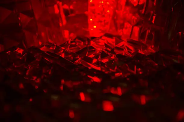 Photo of Close up of cut crystal in mysterious ruby light.Magic shiny background.