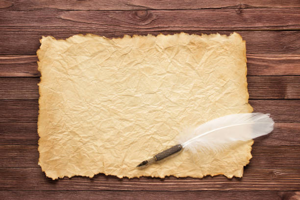 istock White feather and old paper on wood surface 902879666