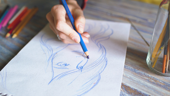 Primer plano de la pintura de la mano femenina bosquejo en cuaderno de papel con lápices. Mujer artista en el trabajo photo