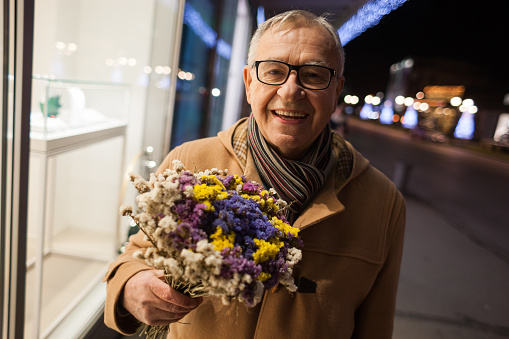 Happy senior man is bringing flowers to his wife.