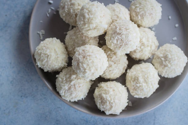 istock Plate with coconut candies on wooden table 902887294