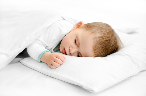 Sleeping baby on white background. Toddler boy in pijama sleeps on white pillow