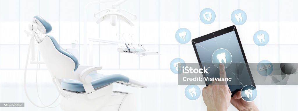 dentist hand touch digital tablet screen teeth icons and symbols on dental clinic with dentist's chair background web banner template contact us concept Dental Health Stock Photo