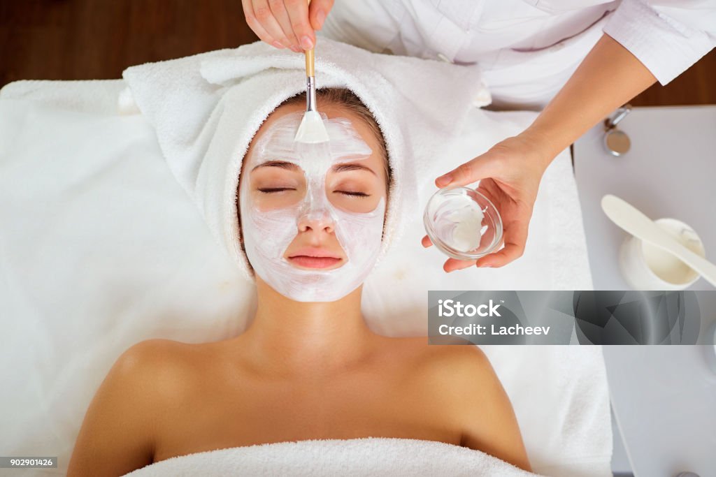 Mujer en la máscara en la cara en el salón de spa - Foto de stock de Máscara facial libre de derechos