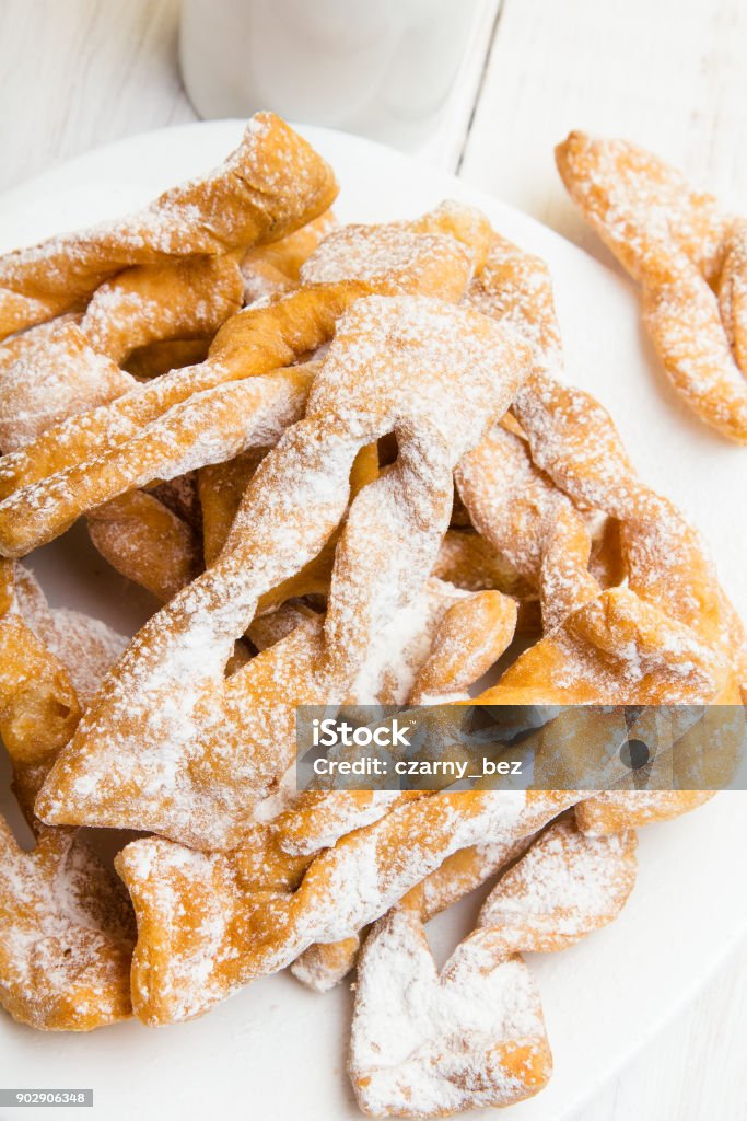 Faworki - Traditional Polish cookies served at Fat Thursday. Cookies and tulip bouquet on white wooden background Faworki - Traditional Polish cookies served at Fat Thursday.  Cookies and tulip bouquet on white wooden background Angel Stock Photo