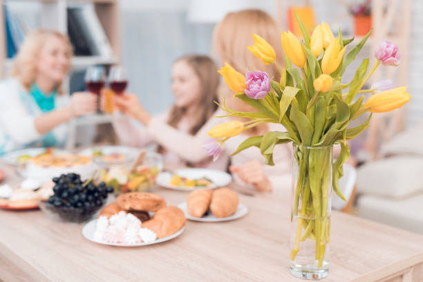 mom and grandmother are drinking wine, a little girl is drinking juice. - drinking little girls women wine imagens e fotografias de stock