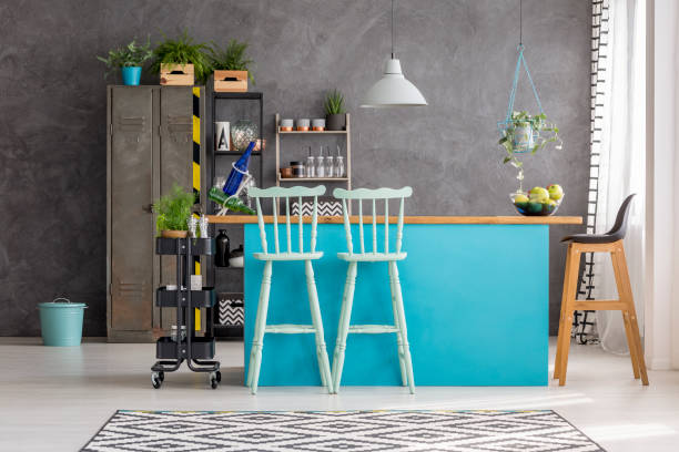 Dining room with bar stools Wooden bar stools and blue dining table under lamp in room with grey wall, metal locker and bucket bar at home stock pictures, royalty-free photos & images