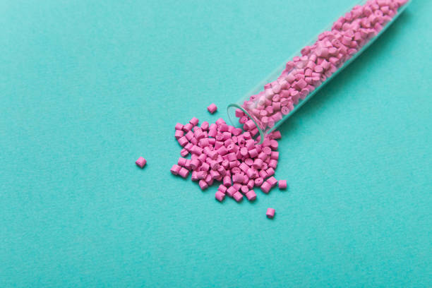 istock Plastic pellets. Pink Plastic granules from the tube on a turquoise background. Plastic Raw material . 902922756