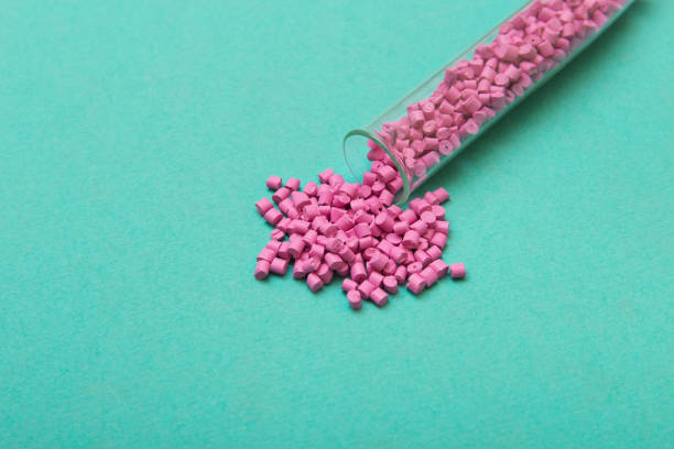 istock Plastic pellets. Pink Plastic granules from the tube on a turquoise background. Plastic Raw material . 902922856