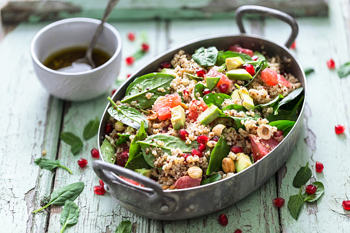 Winter Salad with Quinoa, Avocado, Blood Orange, Pomegranate, Bulgur, Hazelnuts on blue Background