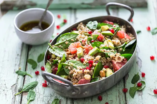 Winter Salad with Quinoa, Avocado, Blood Orange, Pomegranate, Bulgur, Hazelnuts on blue Background