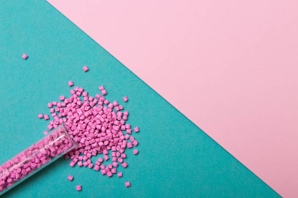 istock Plastic pellets. Pink Plastic granules on the colored geometric background. Plastic Raw material . 902923588