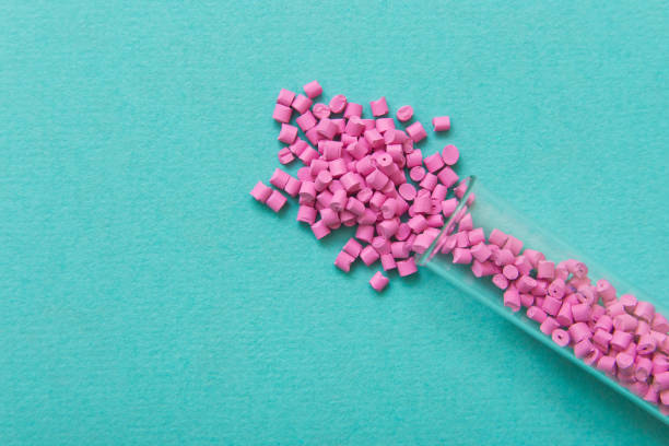 istock Plastic pellets. Pink Plastic granules on a turquoise background. Plastic Raw material . 902925068