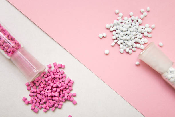 istock Plastic pellets. Pink and white Colorant for plastics on a geometric background. Plastic Raw material . 902925134