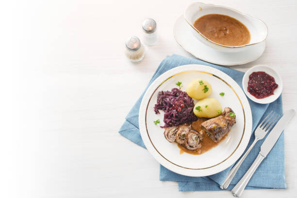 bifes de vitela ou rocambole com repolho roxo, batata e molho num guardanapo azul sobre uma mesa brilhante, fundo desbota para o branco, alto ângulo vista acima, espaço de cópia - sauces sweet sauce cooking traditional culture - fotografias e filmes do acervo