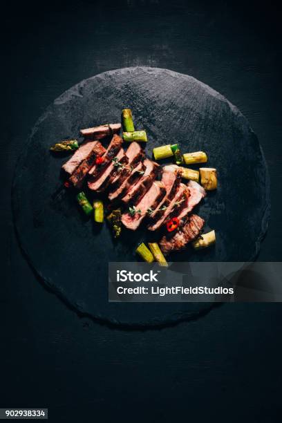 Photo libre de droit de Vue De Dessus De Savoureuses Tranches Viande Grillée Aux Asperges Sur Ardoise Noire banque d'images et plus d'images libres de droit de Haute gastronomie