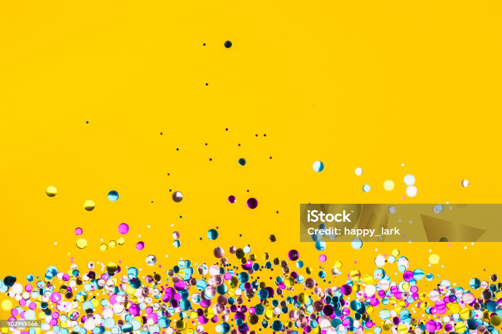 Confettis colorés sur fond jaune - Photo de Anniversaire d'un évènement libre de droits