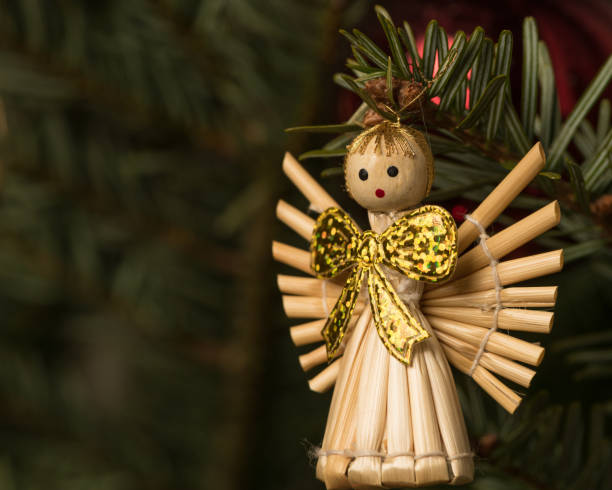 Closeup of an angel made of straw hanging on a christmas tree