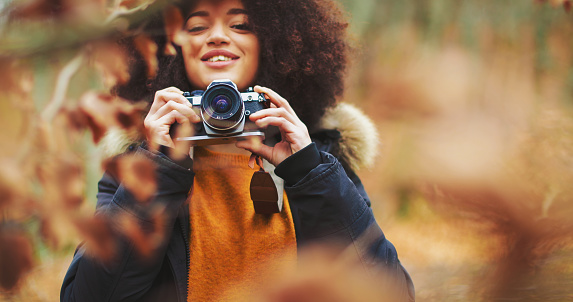Young woman with afro hairstyle taking photos in the woods