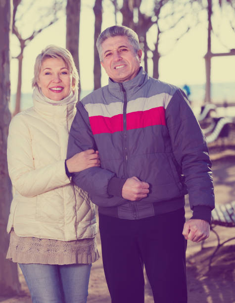 istock Smiling married couple walk in park 902969952