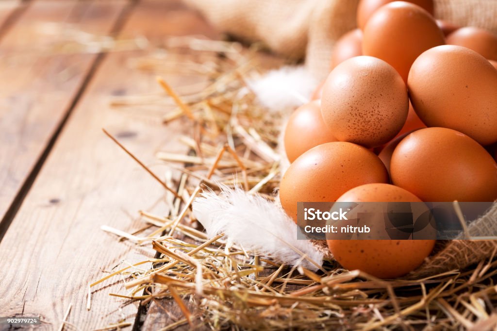 Eggs in a heap of Hay Eggs in a heap of Hay on wooden table Animal Egg Stock Photo