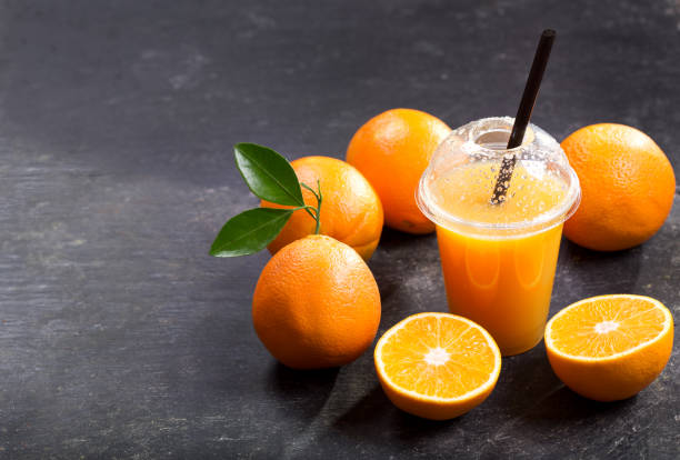 istock cold orange juice in takeaway plastic cup with fresh fruits 902979730