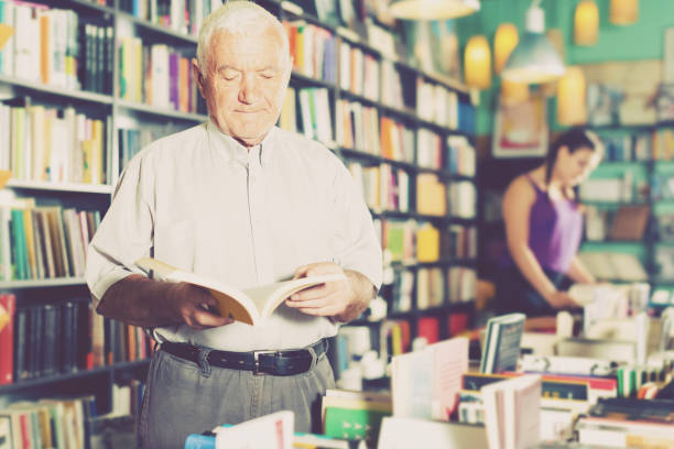 istock Person 53-64 years old is choosing book for reading in free time 902983802