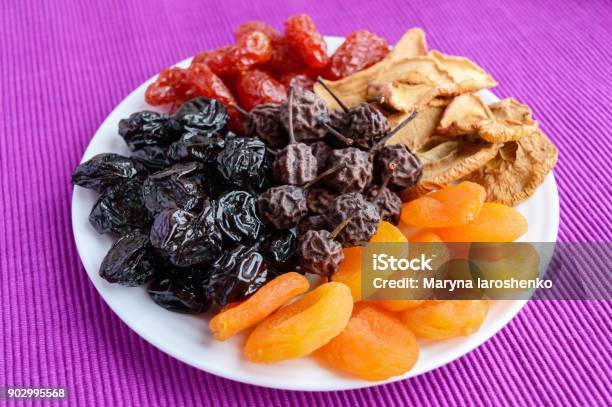 A Pile Of Dried Fruits On A White Plate On A Purple Background Antioxidant Mix A Useful Product Proper Nutrition Harvest Stock Photo - Download Image Now