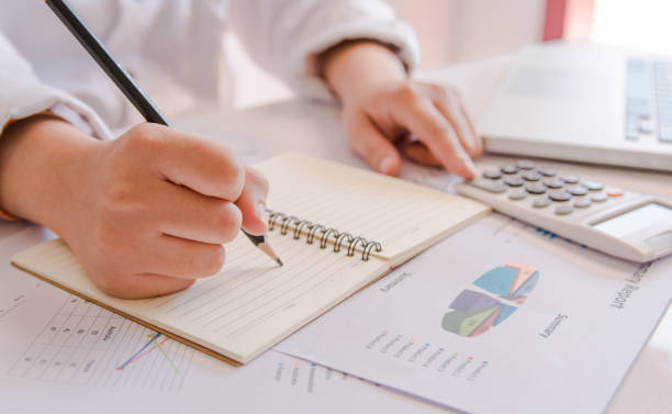istock Close up woman hand using calculator and writing make note with calculate about cost at home office. 902996534