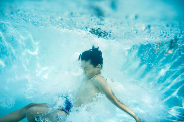 istock Boy swimming underwater in swimming pool 903002982