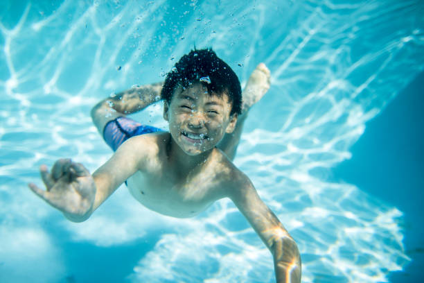 istock Boy swimming underwater in swimming pool 903003014
