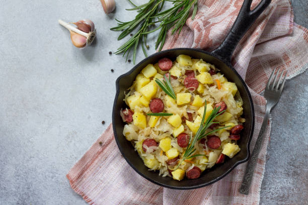 homemade snacks on a stone or slate background. warm salad with potatoes sauerkraut and smoked sausages. flat lay. top view with copy space. - sauerkraut cabbage paprika salad imagens e fotografias de stock