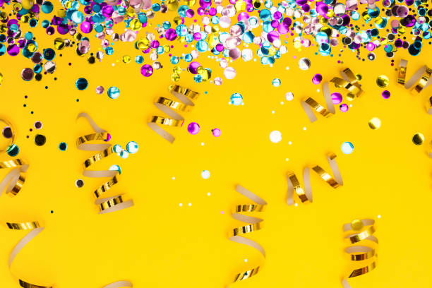 istock Colorful confetti and golden coiled streamers on yellow background 903007362
