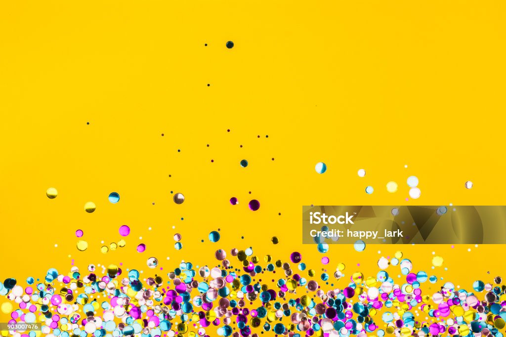 Colorful confetti on yellow background Colorful confetti on yellow background. Holiday frame. Copy space Confetti Stock Photo