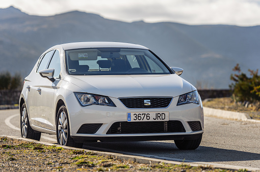 MALAGA, SPAIN - DECEMBER 2017:  White Seat Leon stays parked among clouds on road of Crete island. Seat Leon is a compact hatchback derived from the Seat.