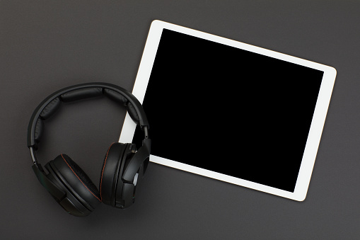 Black headphones and digital tablet on gray background
