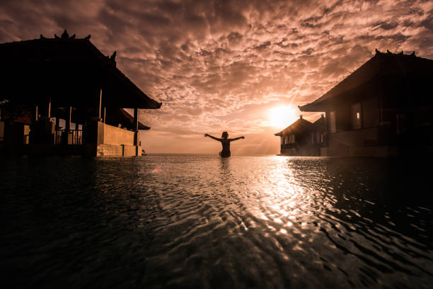 istock Woman sitting whit open arms on edge of infinity pool. 903016144