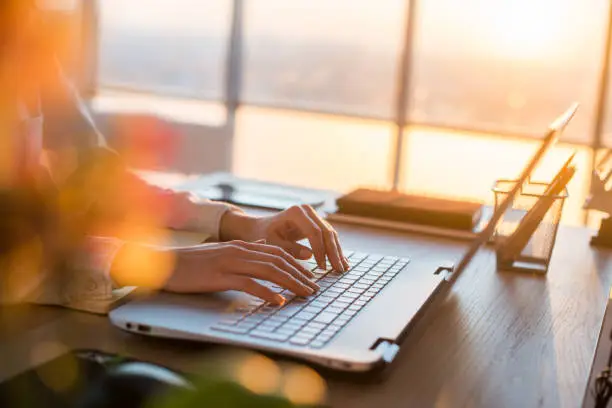 Photo of Female teleworker texting using laptop and internet, working online. Freelancer typing at home office, workplace.