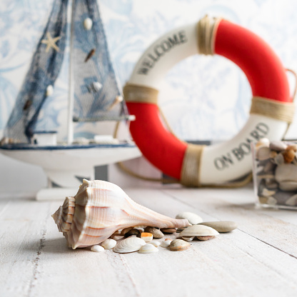 Sea theme decorations of the kids room, such as cute wooden boat, sea shells and stones, and life buoy