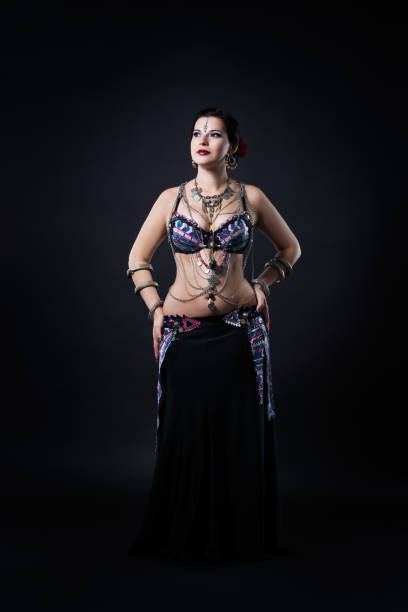 istock Women performs belly dance in ethnic dress on black background 903025424