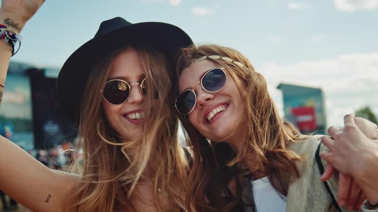 Two girls are together on a music festival. They having a wonderful time.