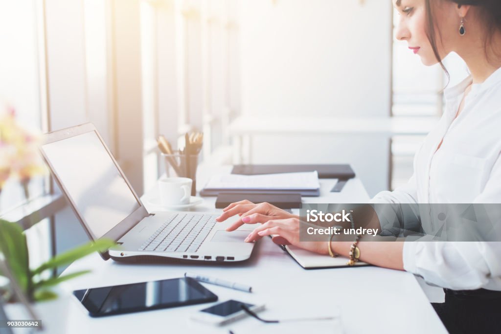 Attractive female assistant working, typing, using portable computer, concentrated, looking at the monitor. Office worker reading business e-mail. Attractive female assistant working, typing, using portable computer, concentrated, looking at the monitor. Office worker reading business e-mail Office Stock Photo